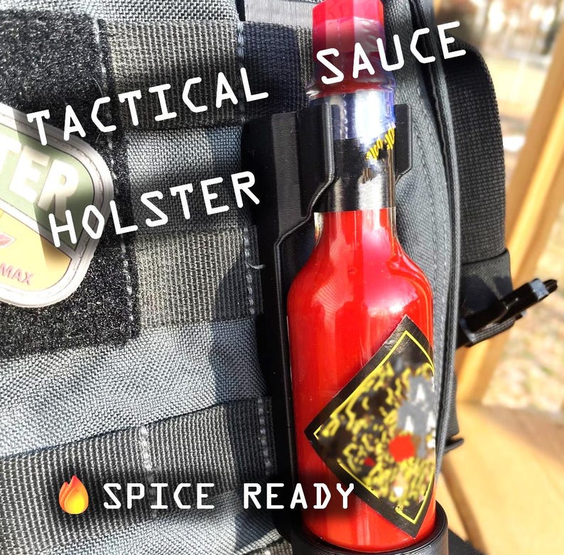 May include: A red hot sauce bottle with a black label and a black and gray tactical holster. The holster is attached to a gray tactical bag. The text "Tactical Holster" and "Spice Ready" are visible on the bag. The text "Sauce" is visible on the bottle.