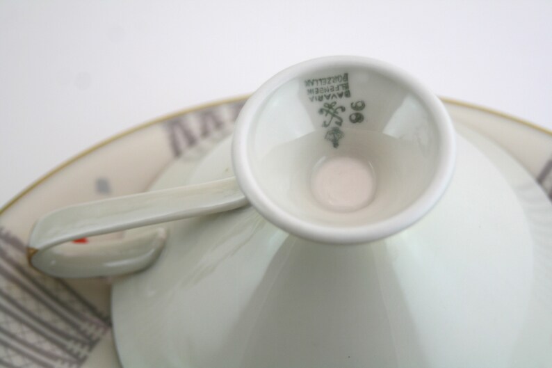 May include: Close-up of the base of a white porcelain teacup with a green mark that reads "Bavaria,  Porzellan,  Rosenthal,  98".