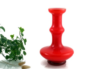 May include: A bright red glass vase with a rounded base and a narrow neck. The vase has a unique design with two bulges in the middle.