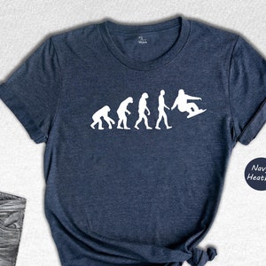 May include: A navy heather t-shirt with a white graphic of the evolution of man ending with a person snowboarding.