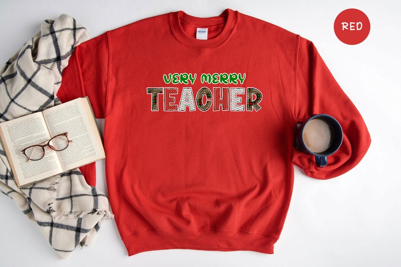May include: Red sweatshirt with the text "Very Merry Teacher" in green and white letters with a red and green plaid pattern.