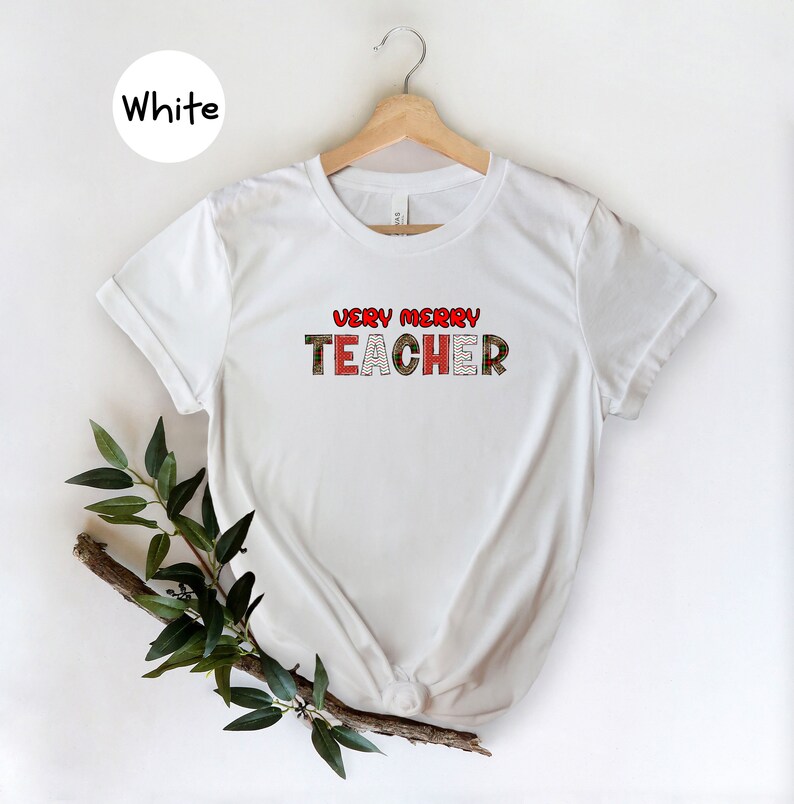 May include: White t-shirt with the text "Very Merry Teacher" in red and green plaid lettering.