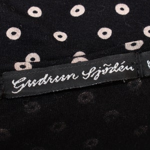 May include: A black fabric with a white polka dot pattern. A black label with white text reads "Gussaroen Sj&auml;zlen" and "M".