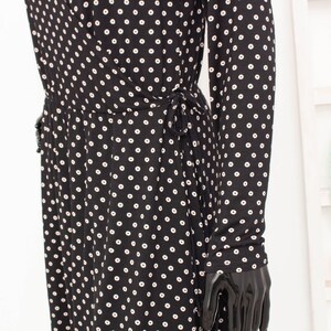 May include: A black and white polka dot dress with long sleeves and a tie at the waist.