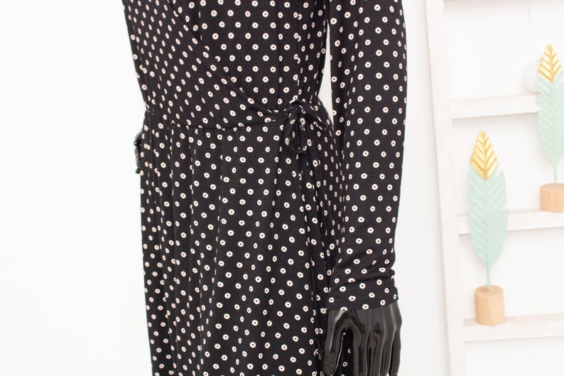 May include: A black and white polka dot dress with long sleeves and a tie at the waist.