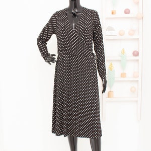 May include: A black wrap dress with a white polka dot pattern and long sleeves.