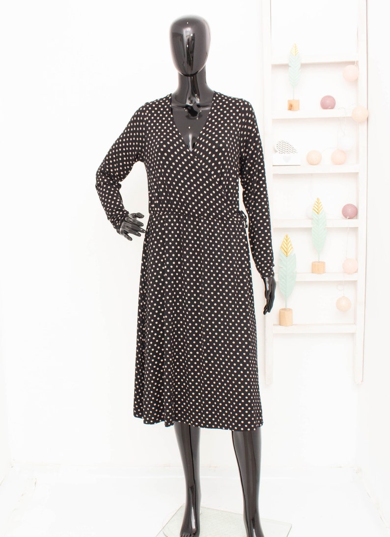 May include: A black wrap dress with a white polka dot pattern and long sleeves.