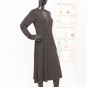 May include: A black midi dress with white polka dots. The dress has long sleeves and a v-neckline.