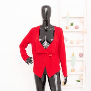Peut inclure: Un cardigan rouge en tricot avec une seule fermeture boutonnée. Le cardigan est drapé sur un mannequin noir.