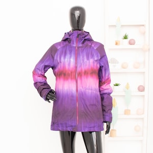 May include: A purple and pink tie-dye ski jacket with a zipper closure and a hood.