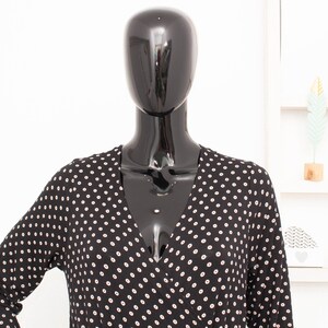 May include: A black and white polka dot long-sleeved dress with a V-neckline.