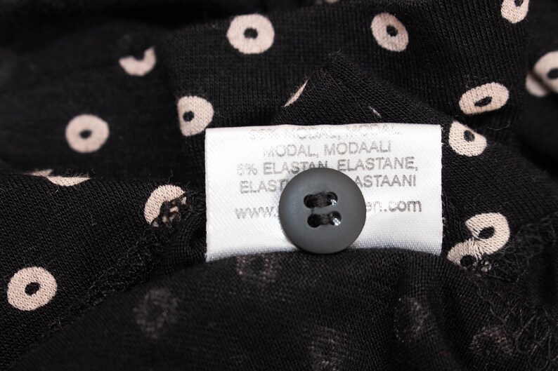 May include: A white fabric tag with black text that reads "Modal, Modaaali 95% Elastan, Elastane, Elasto Astaan, www.en.com". A black button is attached to the tag.