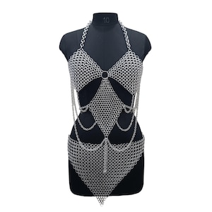 May include: A silver-toned chainmail body harness constructed from interlocking metal rings. The design features a halter-style neckline, two triangular chest panels, a diamond-shaped midsection, and a pointed lower section with draped chain accents.