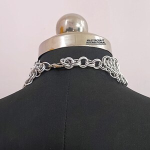 May include: Silver chainmail necklace with a clasp closure. The necklace is displayed on a black mannequin bust. The text "MASTERCRAFT INTERNATIONAL" is visible on the bust.