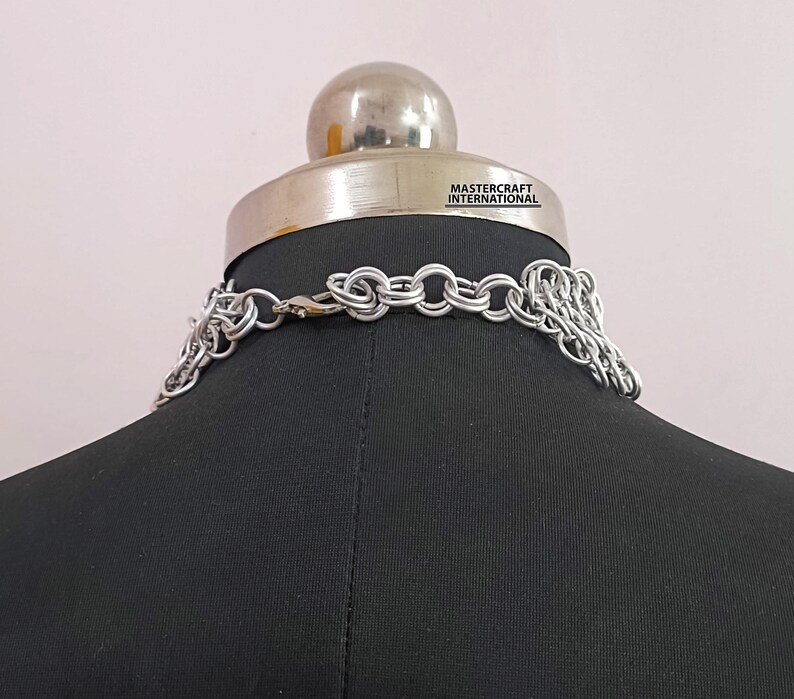 May include: Silver chainmail necklace with a clasp closure. The necklace is displayed on a black mannequin bust. The text "MASTERCRAFT INTERNATIONAL" is visible on the bust.