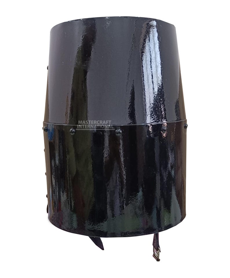 Op de afbeelding: Een zwarte, cilindrische helm met een glanzende afwerking. De helm heeft een geklonken band en een leren riem met een gesp. De tekst "MASTERCRAFT INTERNATIONAL" is zichtbaar. Historisch item.