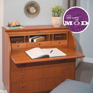 May include: A vintage wooden desk with a drop-down writing surface, three drawers, and a small chair. The desk has a light wood finish and the chair has a blue fabric seat.