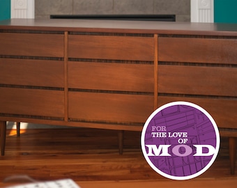May include: A mid-century modern dresser with six drawers, crafted from warm-toned wood. The dresser features a rectangular design with tapered legs and dark accents. The image includes a circular logo that says "FOR THE LOVE OF MOD".