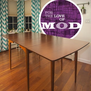 May include: A mid-century modern dining table with a wood top and tapered legs. The table is set in a room with wood floors and teal chevron patterned curtains. A circle with the text "FOR THE LOVE OF MOD" is superimposed on the image.