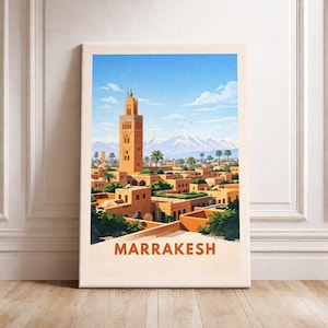 May include: A framed canvas print featuring a vibrant illustration of Marrakech. The artwork depicts a cityscape with a tall minaret, buildings, palm trees, and snow-capped mountains under a bright blue sky. The word "MARRAKESH" is printed at the bottom.