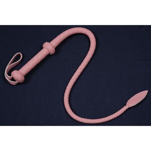 May include: A pink leather whip with a braided handle and a pointed tip.