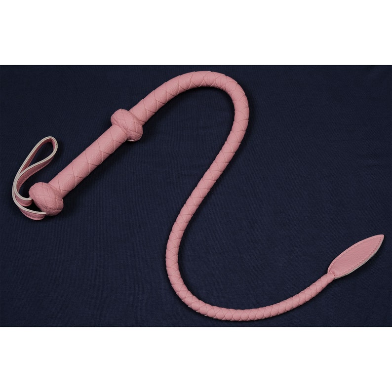 May include: A pink leather whip with a braided handle and a pointed tip.