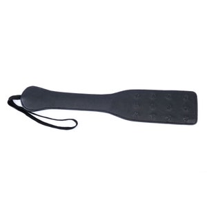 May include: A black leather paddle with a strap. The paddle has a textured surface.