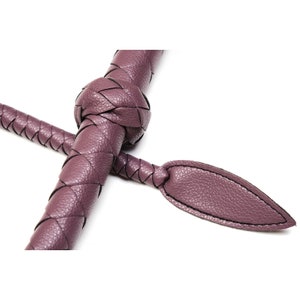 May include: A purple braided leather whip with a knotted handle and a pointed tip.