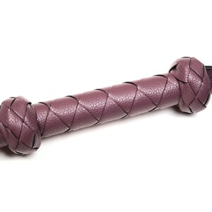 May include: A purple leather whip with a braided design.