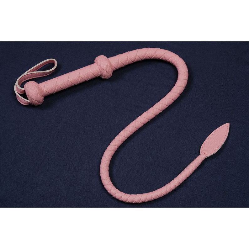 May include: A pink leather whip with a braided design and a pointed tip.