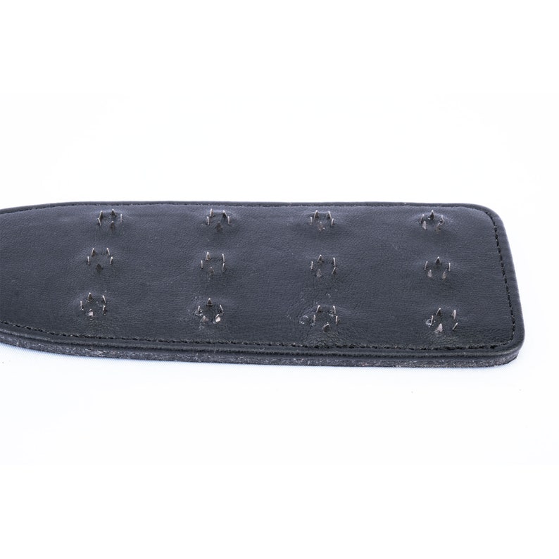 May include: Black leather paddle with multiple rows of metal studs.