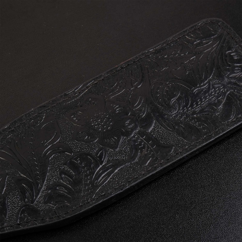 Puede incluir: Una correa de cuero negra con un dise&ntilde;o floral en relieve. La correa est&aacute; hecha de cuero de alta calidad y tiene un acabado liso y pulido.