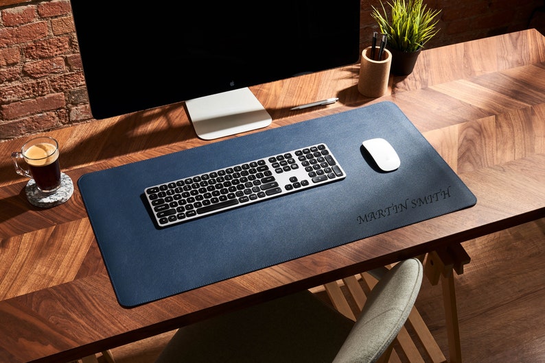 May include: A blue leather desk mat with a silver keyboard and a white mouse. The mat has the name "MARTIN SMITH" embossed in the lower right corner.