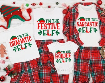 May include: A set of four white t-shirts with red and green Christmas elf designs. The shirts have the text "I'm the Festive Elf", "I'm the Sarcastic Elf", "I'm the Dramatic Elf", and "I'm the Boujee Elf".