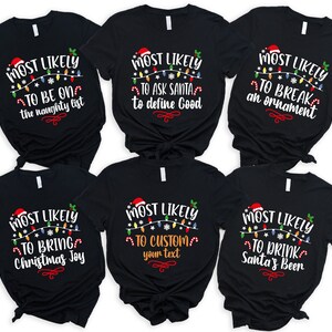 Op de afbeelding: Zes zwarte T-shirts met witte tekst en afbeeldingen. Elk shirt heeft een andere kerstzin, zoals "Most Likely to Be on the Naughty List" en "Most Likely to Drink Santa's Beer".