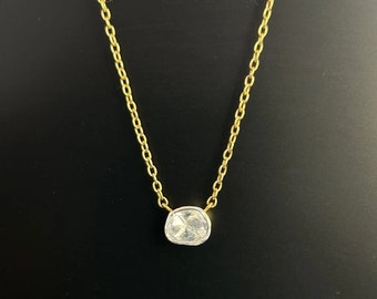 Puede incluir: Un delicado collar de cadena de oro con un solo colgante redondo de piedra preciosa transparente.