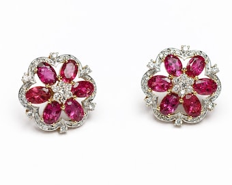 May include: A pair of floral-shaped stud earrings crafted in silver and gold, each featuring six oval-cut vibrant pink gemstones arranged in a petal pattern around a central cluster of small, clear, round-cut white diamonds.