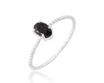 May include: A silver ring featuring a black oval gemstone set in the centre. The band is twisted and has a delicate design.