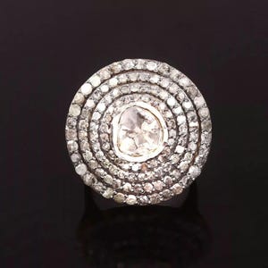 May include: A silver ring with a large, round, faceted, white gemstone surrounded by a halo of smaller, white gemstones.