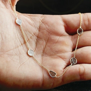May include: A gold chain necklace with five clear, faceted, teardrop-shaped stones.