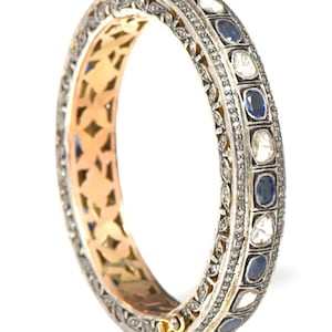 Pode incluir: Um bracelete de prata com um design decorativo que apresenta safiras azuis e diamantes brancos. O bracelete tem um fecho de dobradiça.