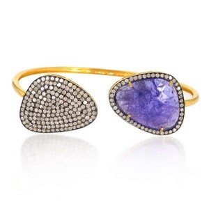 May include: A gold bangle bracelet with two teardrop-shaped stones. One stone is a purple amethyst and the other is a clear diamond.