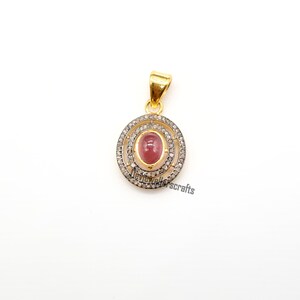 May include: A gold pendant with a pink oval gemstone surrounded by two rows of small diamonds.