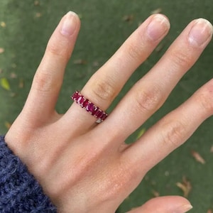 Op de afbeelding: Een rode robijn-eternityband met een gepolijste afwerking. De ring is bezet met kleine, rechthoekige robijnen.