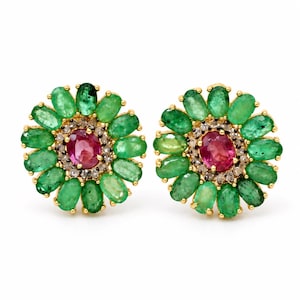 May include: A pair of flower-shaped stud earrings featuring a central oval-cut pink gemstone surrounded by a halo of small white diamonds and an outer ring of oval-cut green emerald petals, all set in a yellow gold metal frame.