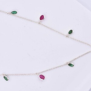May include: A silver chain necklace with alternating green and pink oval-shaped gemstones hanging from it.