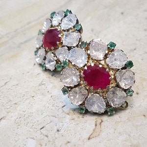 Puede incluir: Un par de pendientes de plata con una piedra preciosa de rubí rojo rodeada de diamantes blancos y esmeraldas verdes.