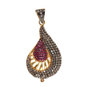 May include: A gold and silver pendant with a teardrop shape. The pendant is decorated with small, clear and brown diamonds and a red ruby in the center.