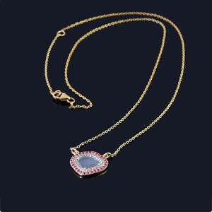 May include: A gold chain necklace with a pendant featuring a clear gemstone surrounded by a double row of pink gemstones.