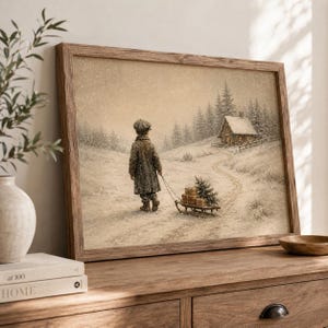 May include: A framed wall art print depicting a snowy winter landscape with a person in a long coat pulling a wooden sled loaded with small wrapped packages and a small evergreen tree toward a rustic cabin nestled among pine trees.
